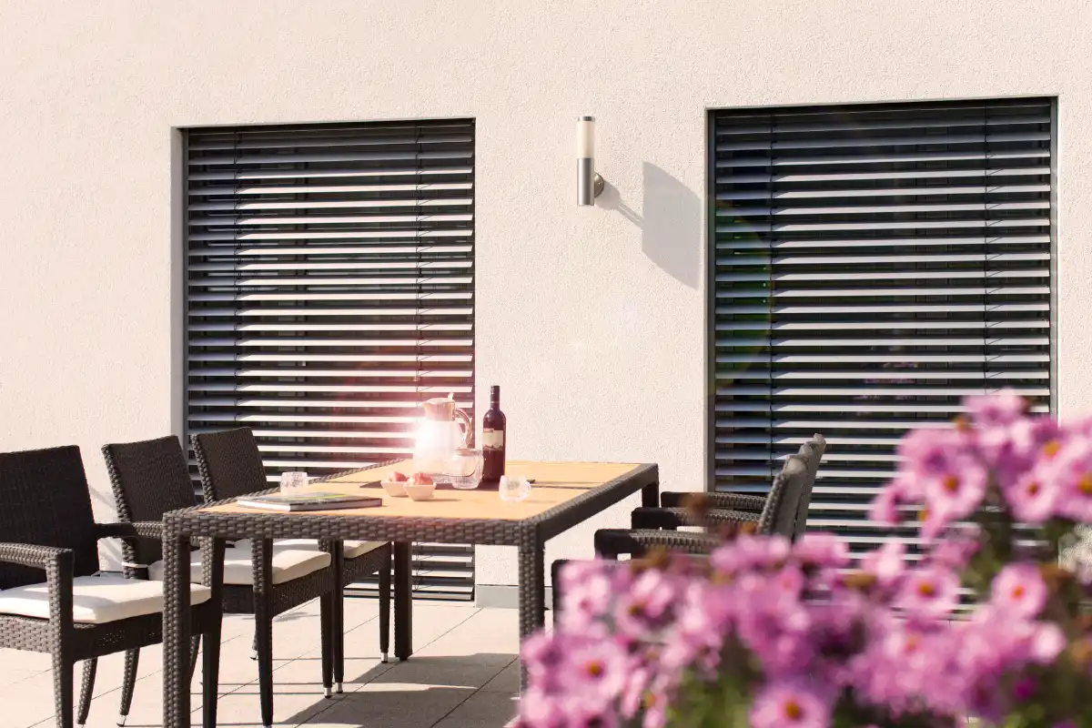 Stilvolle Terrasse mit Außenjalousien Moderne Terrasse mit Möbeln und dekorativen Blumen im Vordergrund